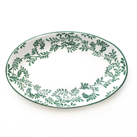 Oval ceramic platter with green leaf pattern on a white background