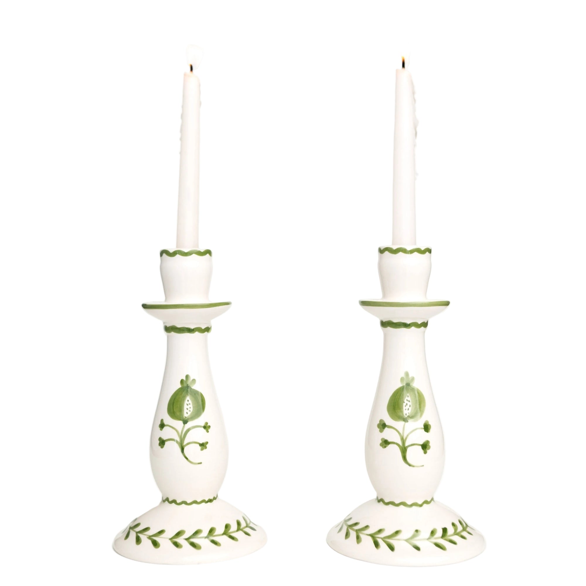 Pair of white candlesticks with green decorative patterns on a white background