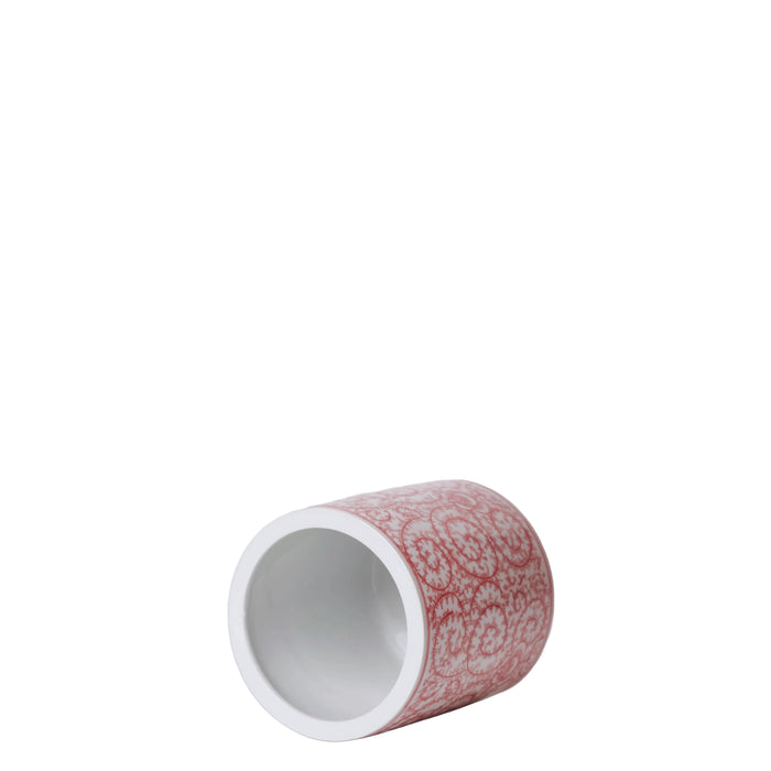 Cylindrical ceramic item with red and white pattern on a gray background