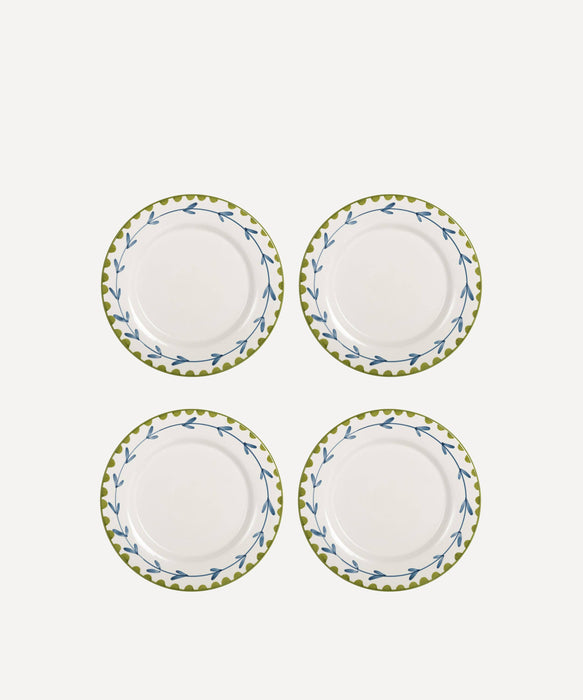 Set of four white plates with green floral rims on a white background