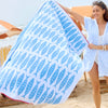 Woman holding a beach towel with fish pattern on a sandy background