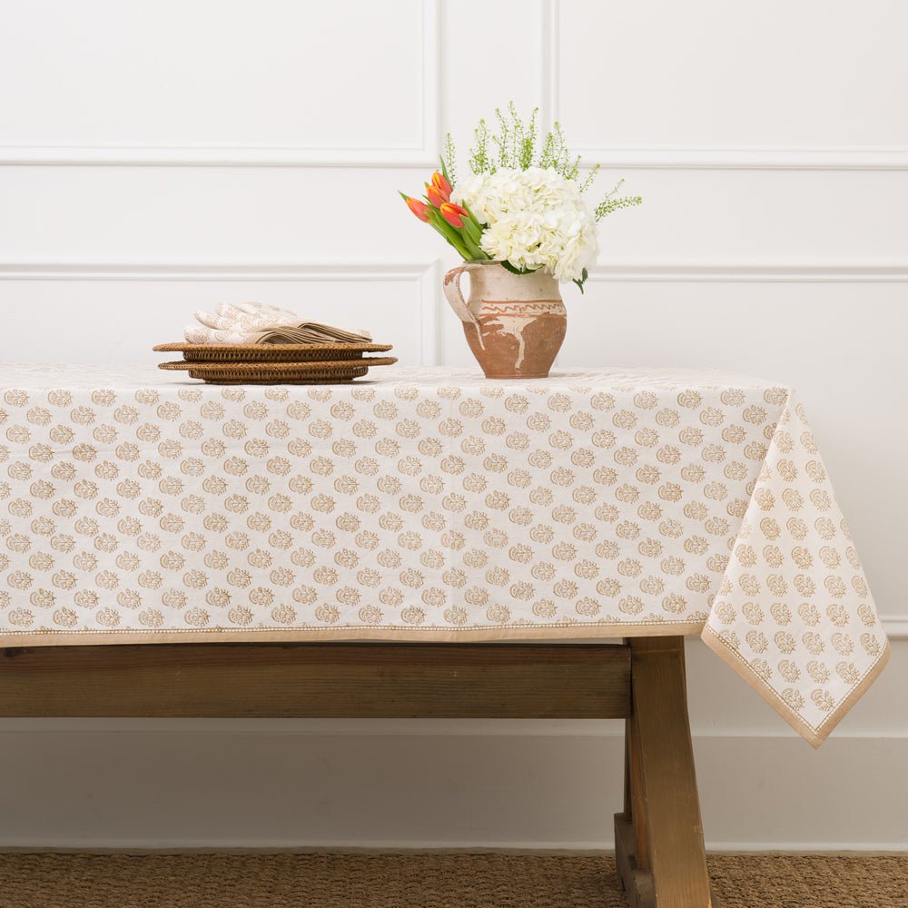 Beige motif tablecloth on table with vase. 