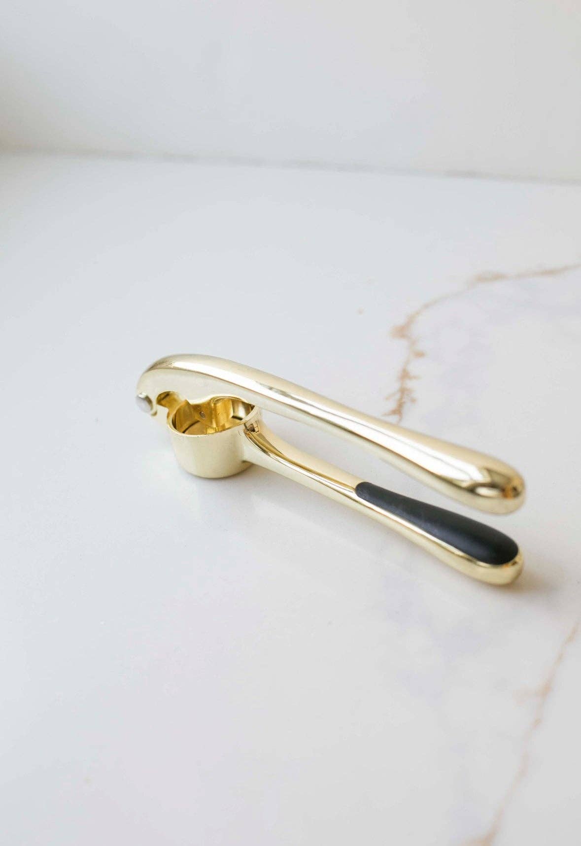 Atelier black and gold garlic press with non-slip silicone handle.