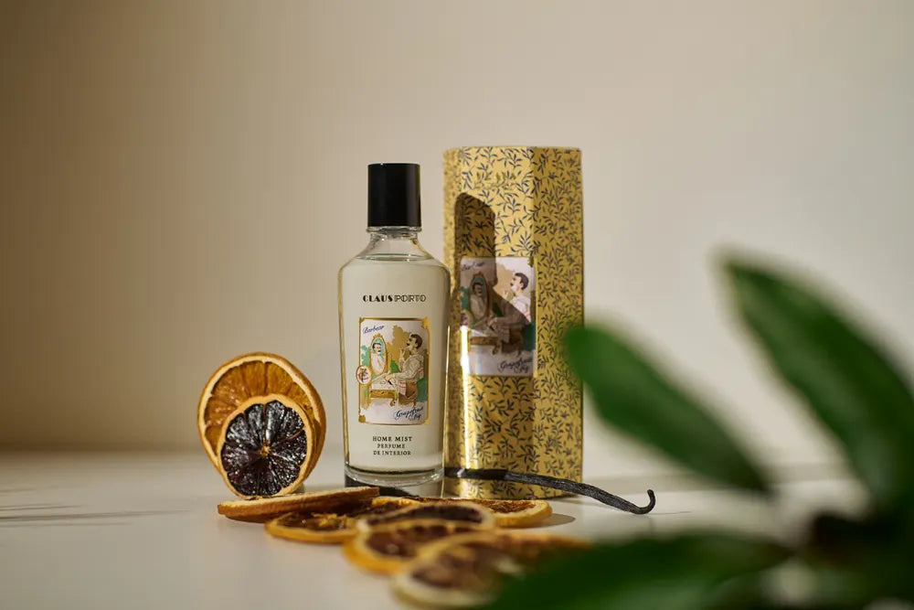 Bottle of aftershave with a decorative box and dried oranges on a table.