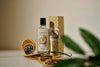 Bottle of aftershave with a decorative box and dried oranges on a table.