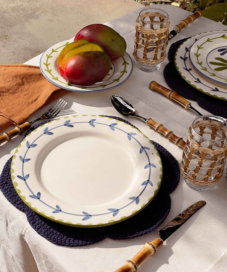 Table setting with plates, glasses, and fruit on a white tablecloth.