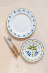 Ceramic plates with decorative borders and floral patterns, accompanied by a knife and fork on a beige background.