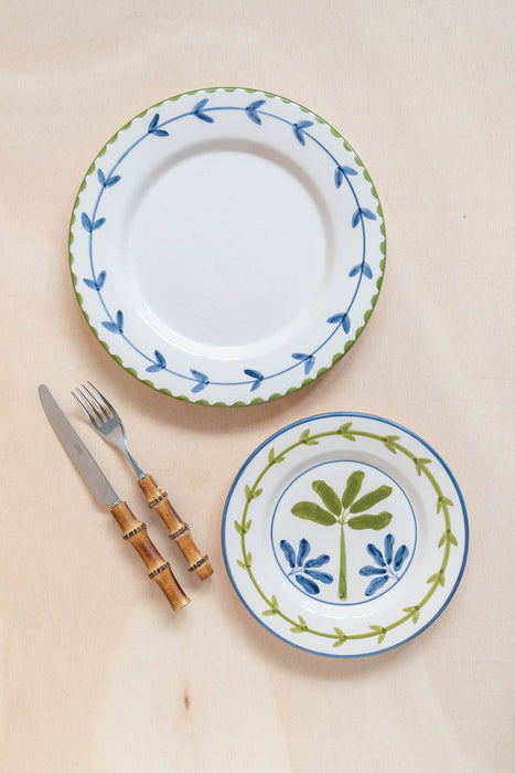 Ceramic plates with decorative borders and floral patterns, accompanied by a knife and fork on a beige background.