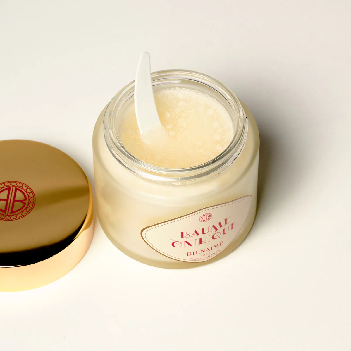 Jar of cream with a spoon inside, featuring a brand logo on a light background