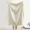 Person holding a beige blanket in a minimalistic room.