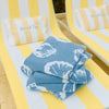 Stack of blue towels with white patterns on a yellow and white striped chair