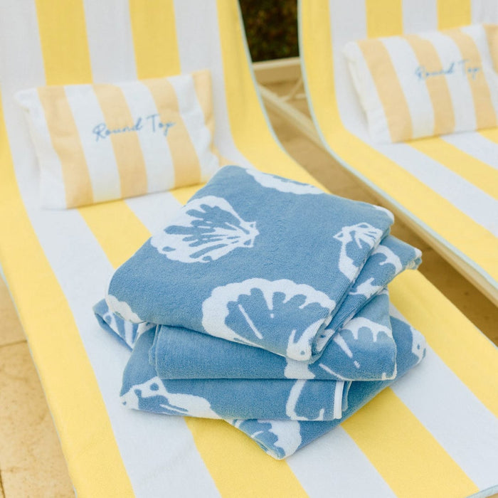 Stack of blue towels with white patterns on a yellow and white striped chair