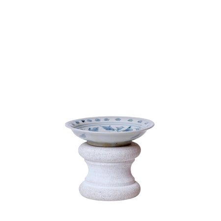 Ceramic bowl with blue patterns on a textured pedestal against a white background