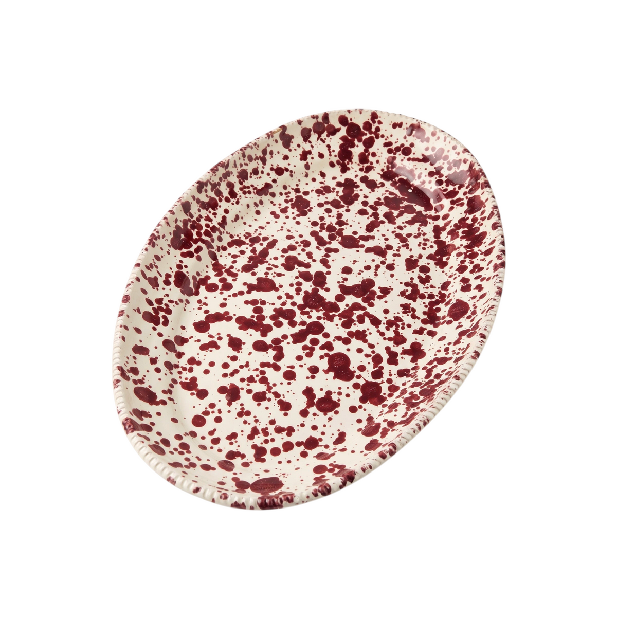 Homeport oval ceramic serving platter with a cream base and bordeaux red splatter pattern and textured rim.