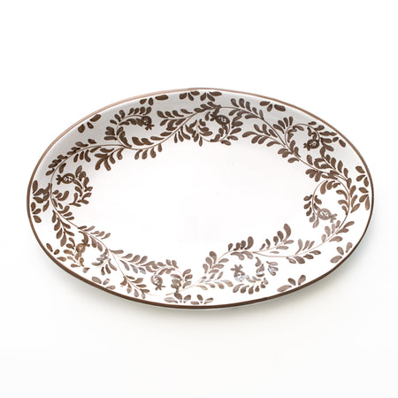 Oval ceramic platter with brown leaf pattern on a white background
