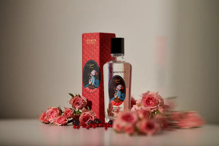 Perfume bottle with red packaging and flowers on a neutral background