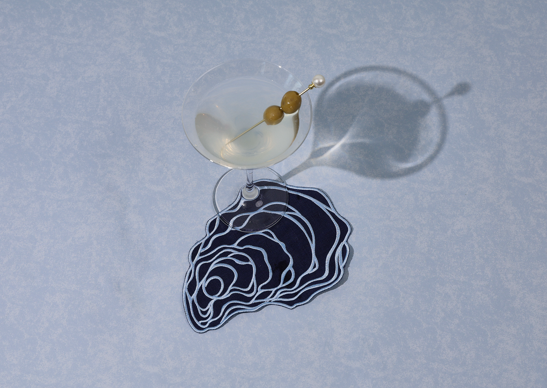 One blue linen oyster cocktail napkin with drink on blue background 