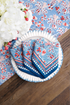Set of blue and red patterned napkins on a white plate with a floral tablecloth in the background.
