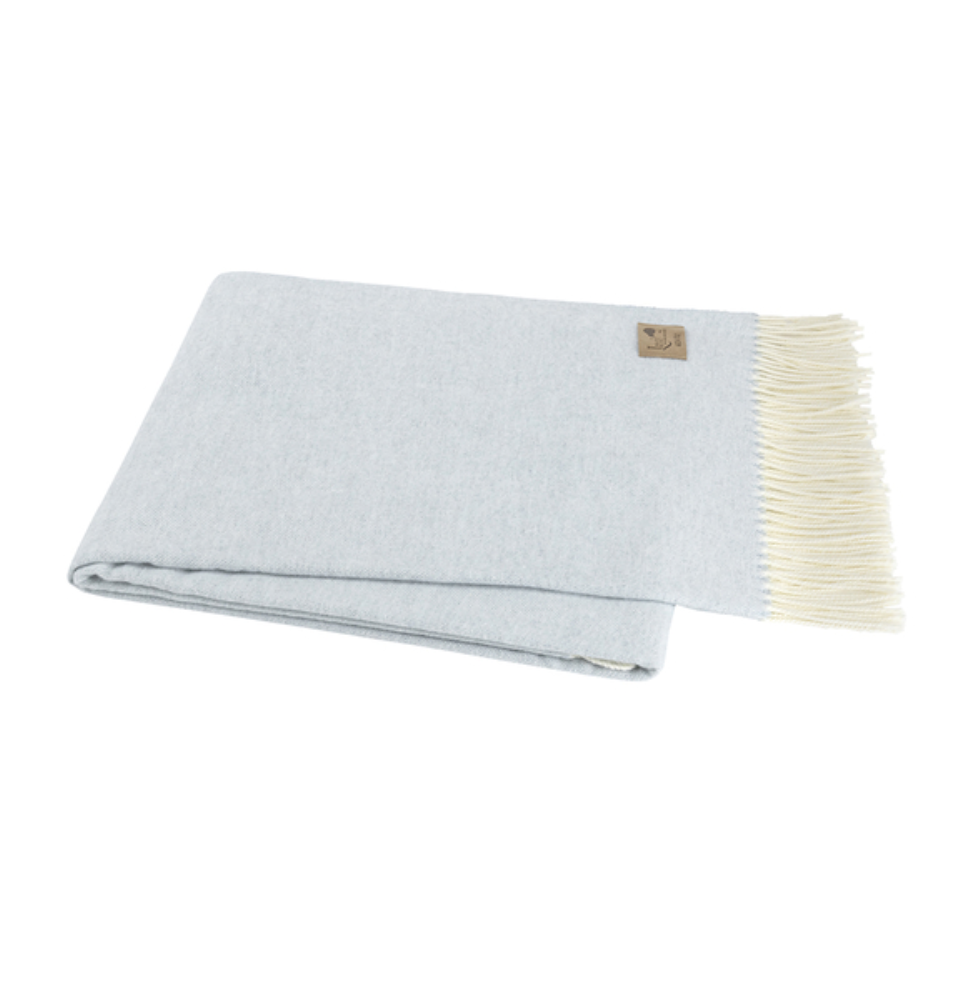 Light blue woven blanket with white fringe on a white background