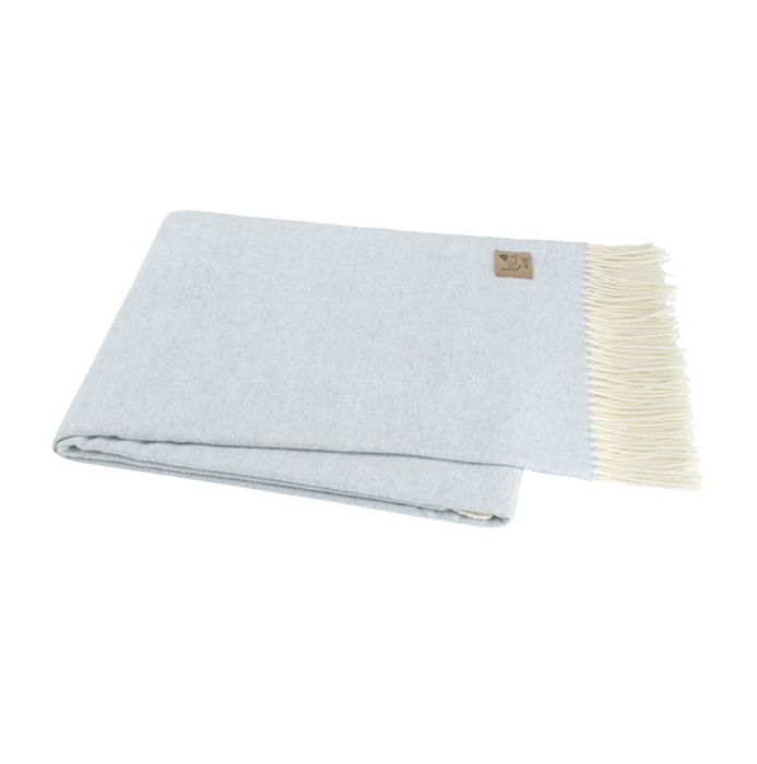 Light blue woven blanket with white fringe on a white background