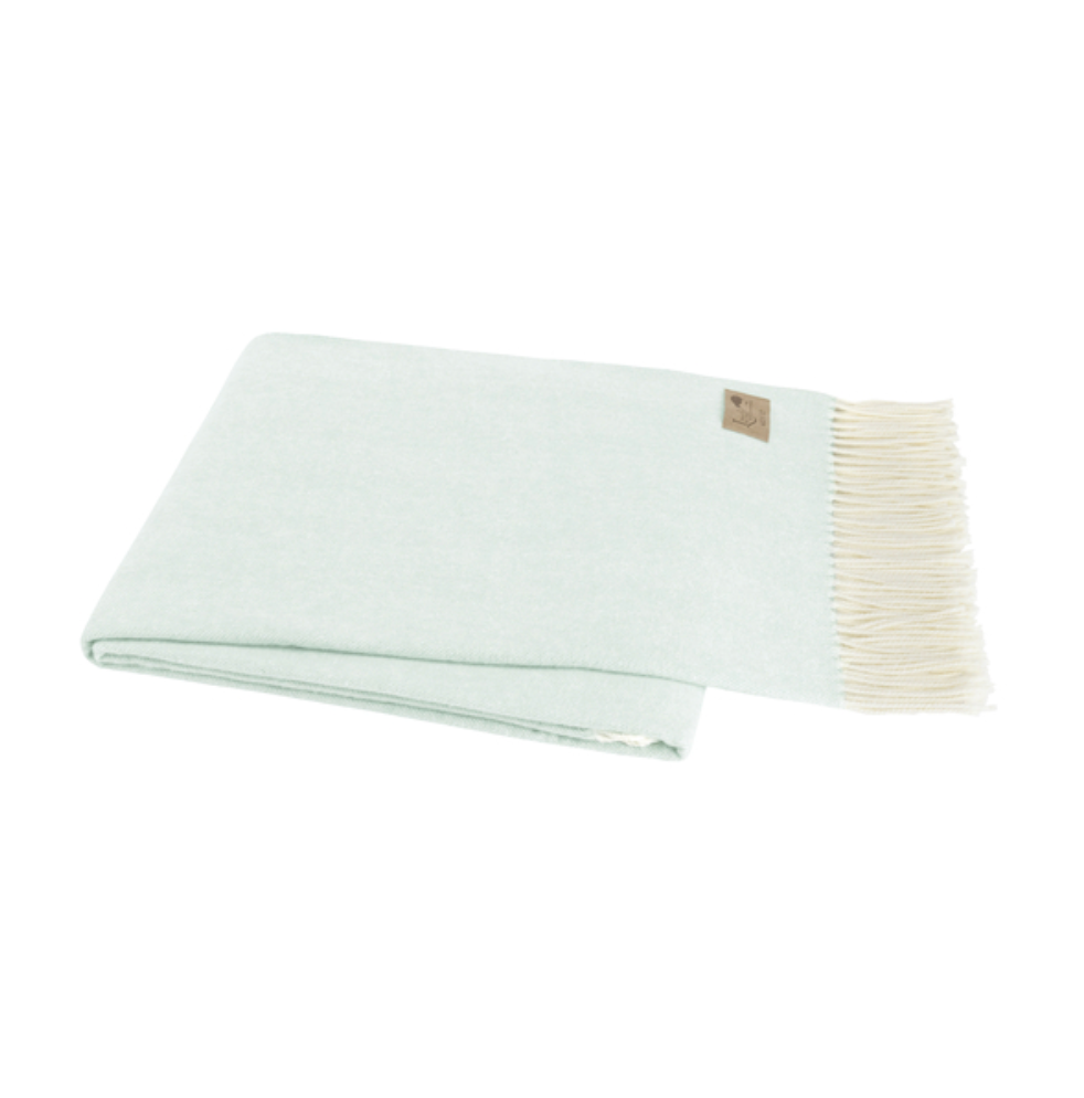 Light green blanket with white trim on a white background