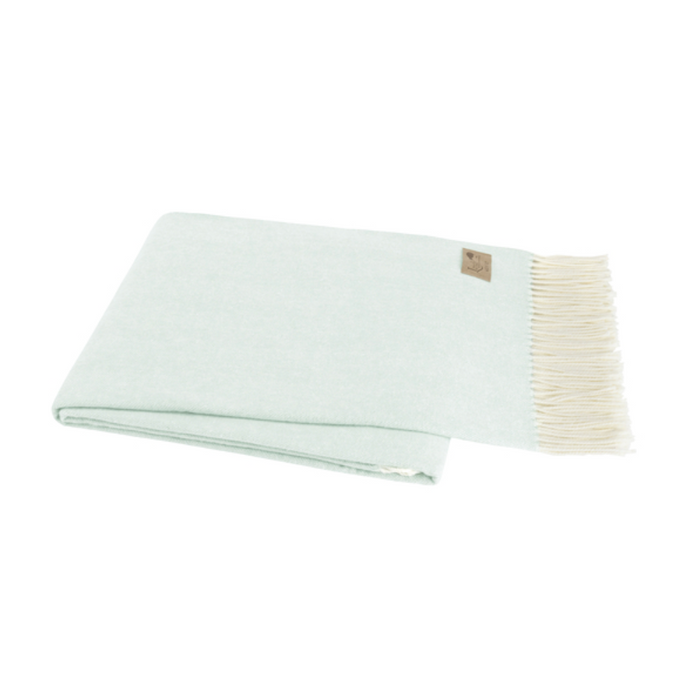 Light green blanket with white trim on a white background