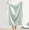 Light blue towel with fringe held by a person on a white background
