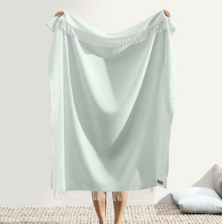 Light blue towel with fringe held by a person on a white background