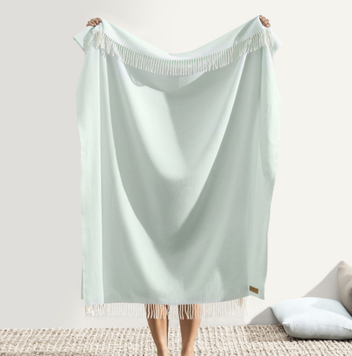 Light blue towel with fringe held by a person on a white background