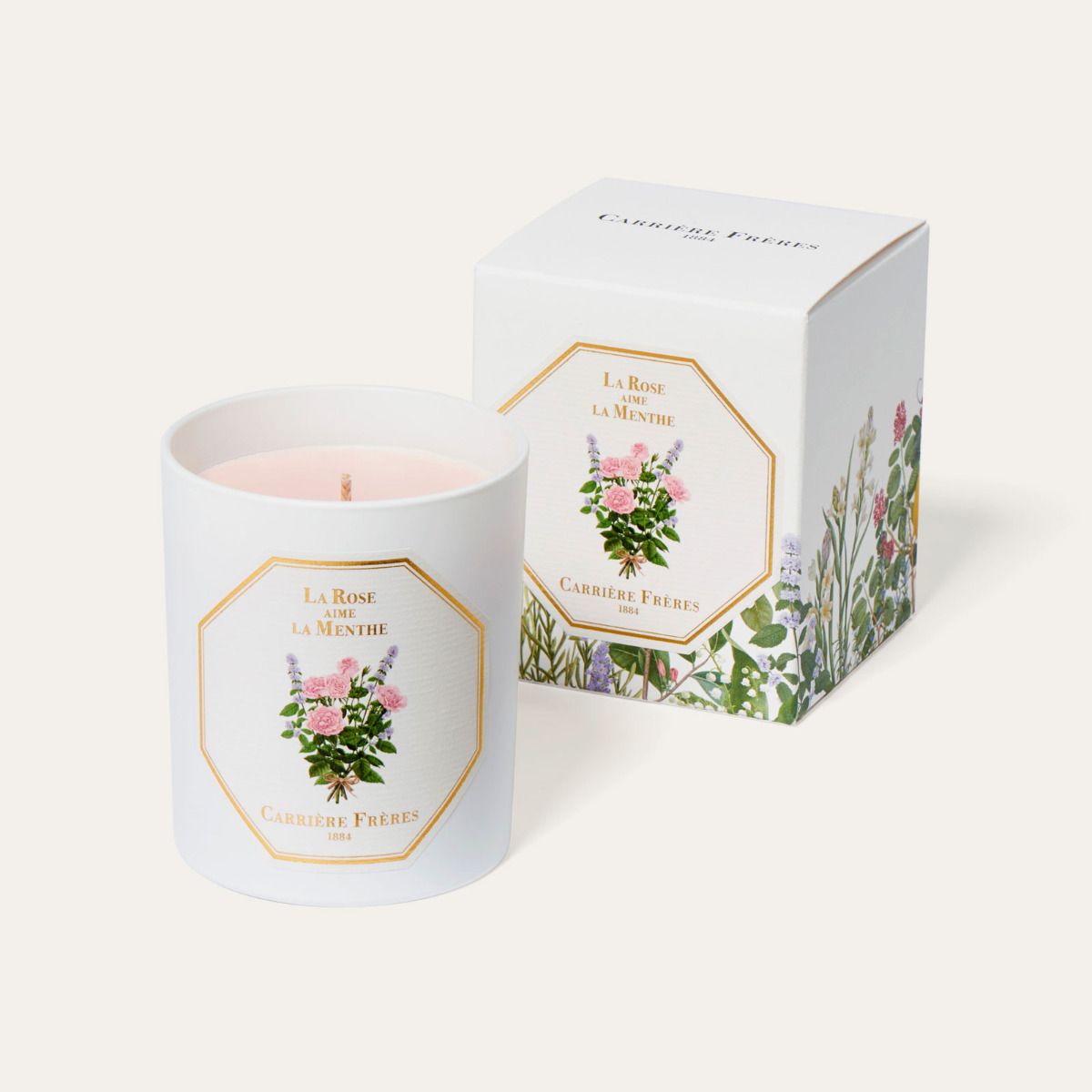A candle with floral and mint design, placed inside a white box with a gold design and the text 'La Rose aime la Menthe'.