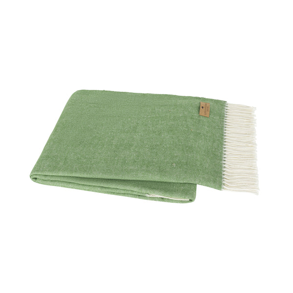 Green blanket with white fringe on a white background