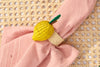 Yellow crocheted lemon-shaped napkin ring on a pink napkin with a woven background