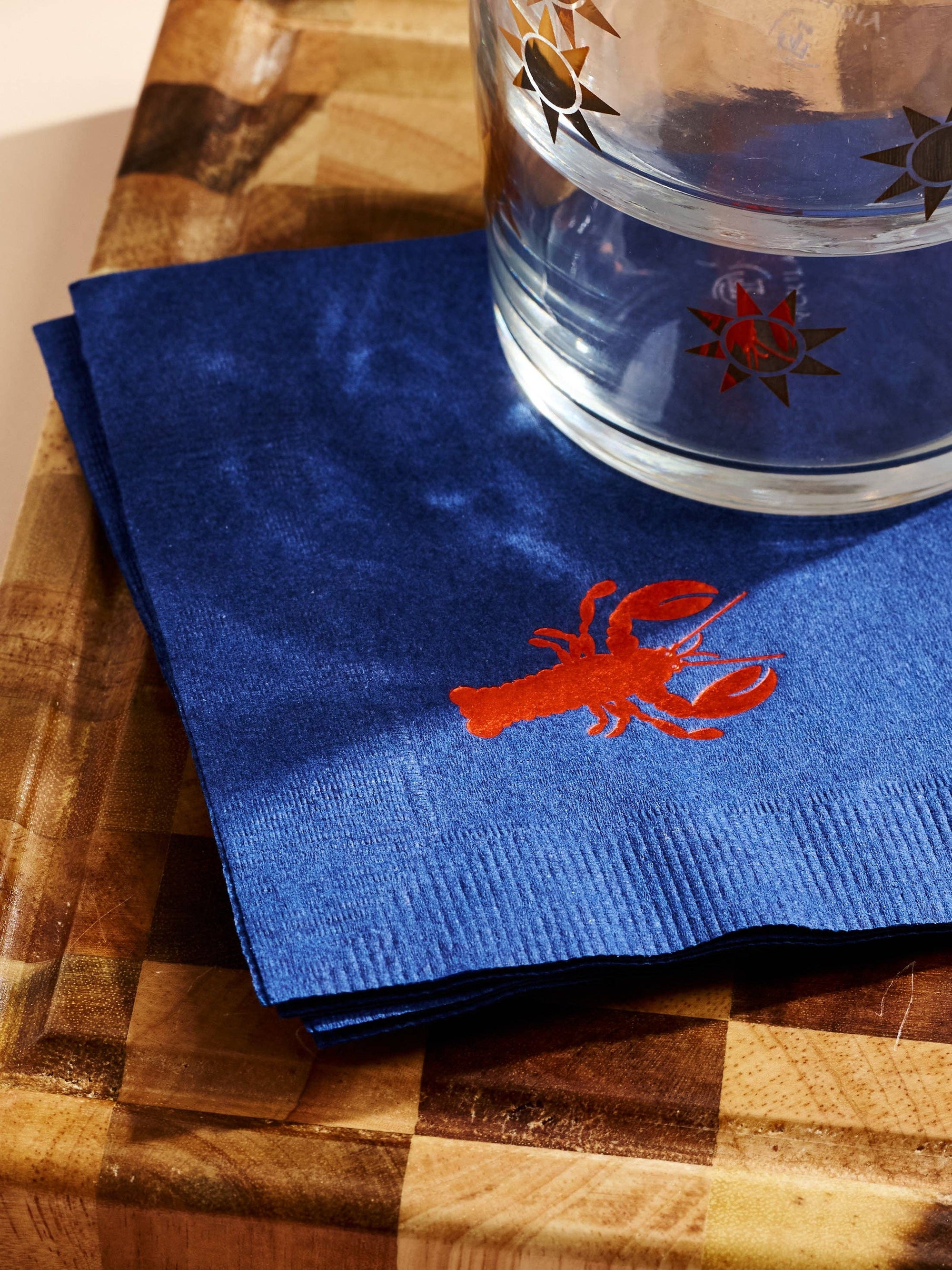 Blue napkin with a red lobster design on a wooden surface