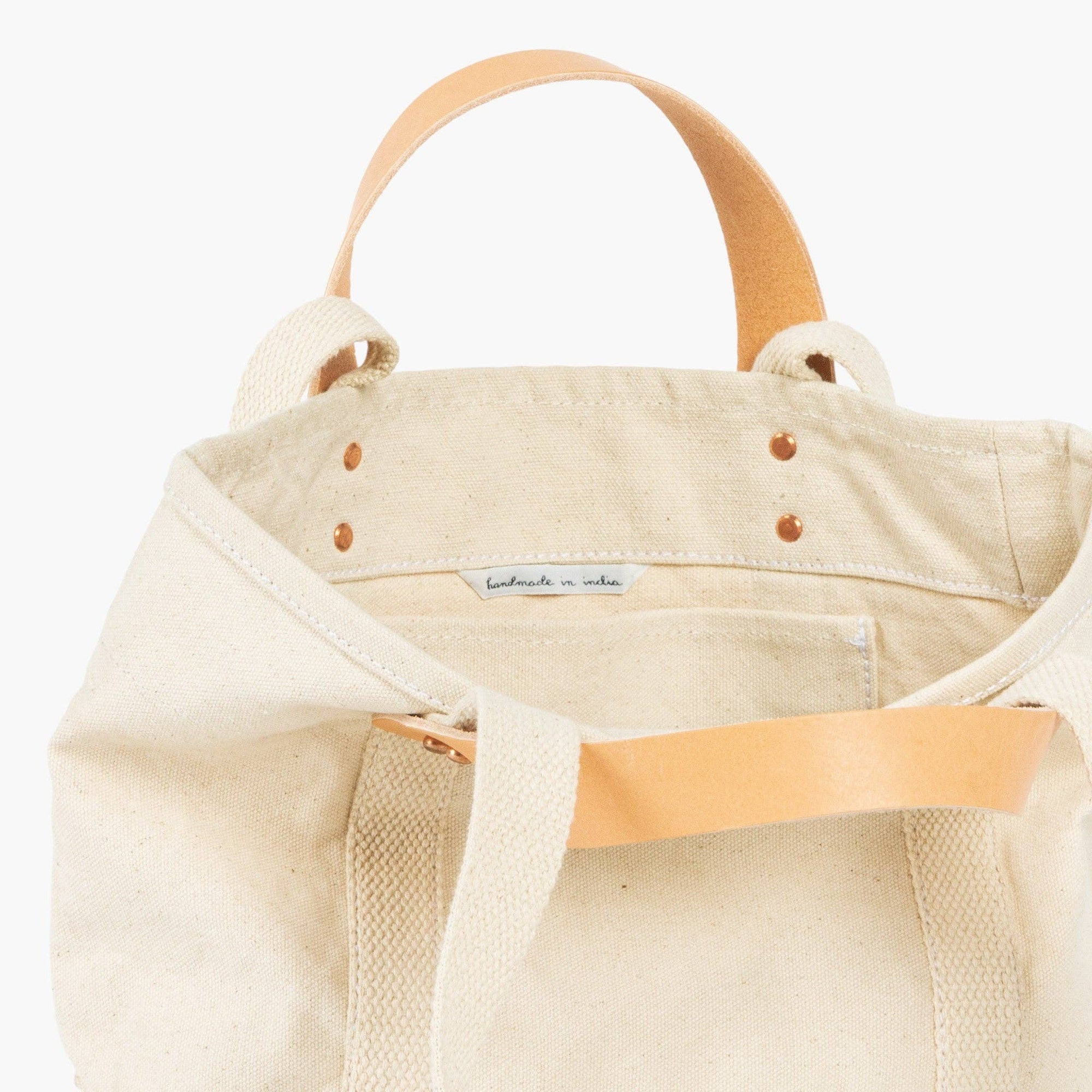 Lunch tote in natural with inside pocket and leather handles and canvas shoulder strap on white background 