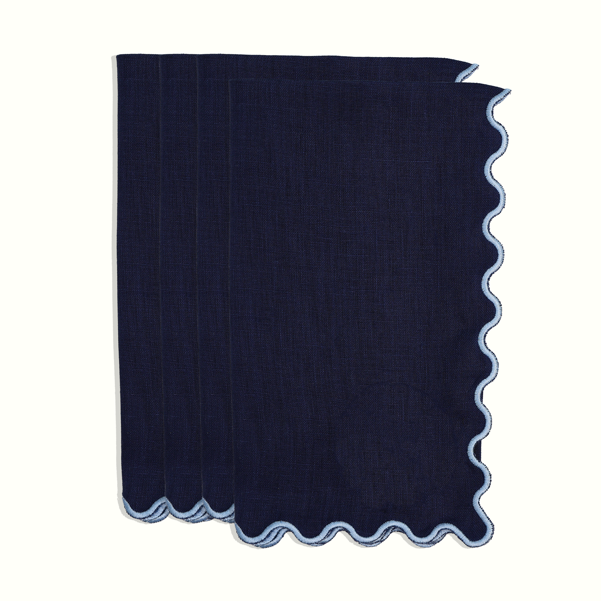 Set of navy linen dinner napkins with light blue scalloped edge on white background 