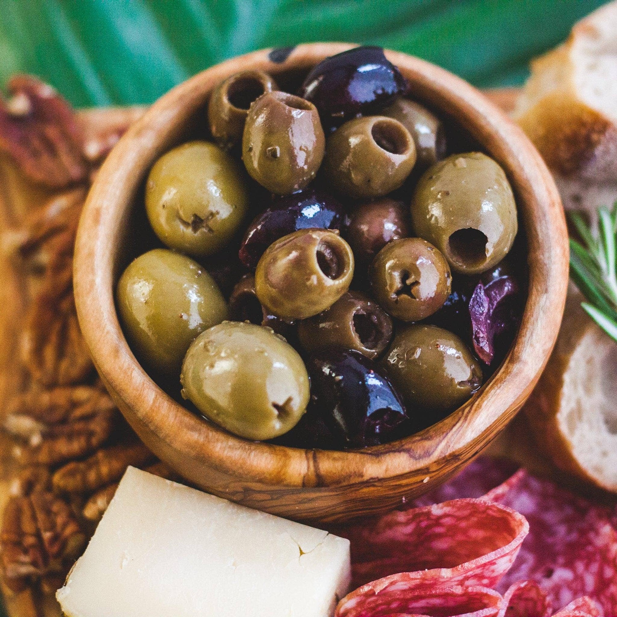 Small olive bowl of wood with olives in it on board