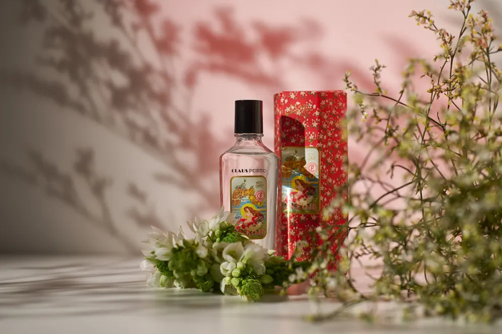 Bottle and box of Caudalie skincare product with flowers on a table