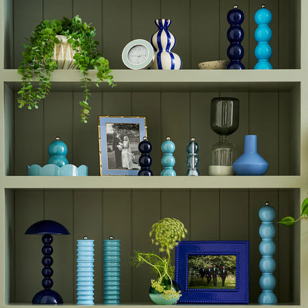 Decorative shelves with various items including vases, a lamp, and framed photos against a green paneled wall.