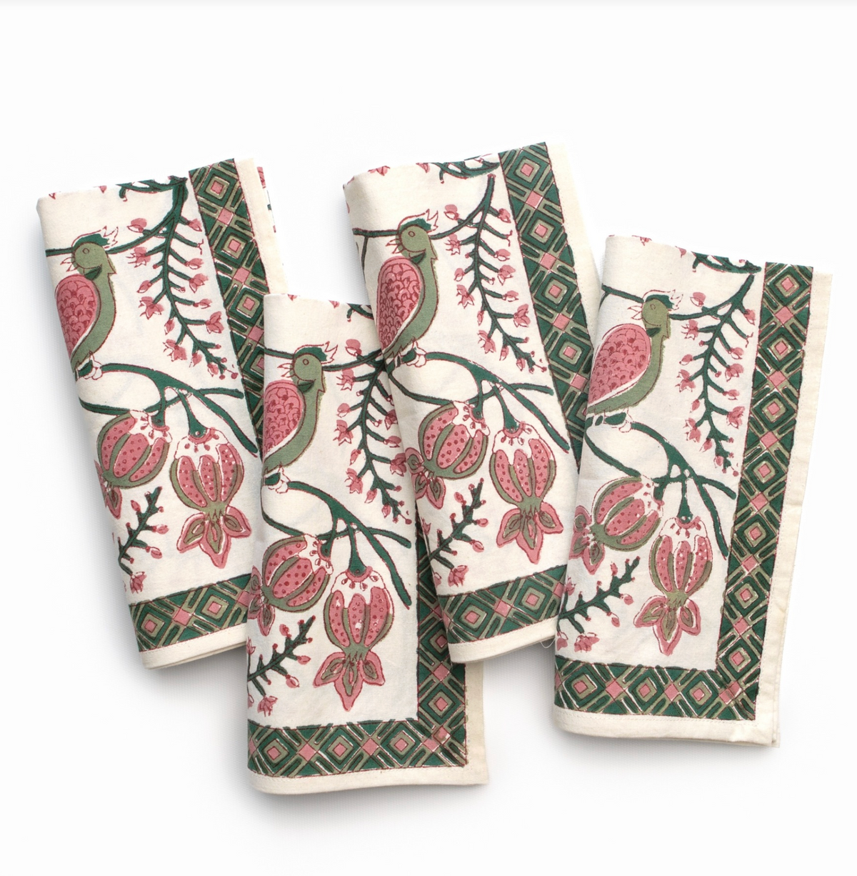 Four folded cotton napkins with a traditional block-print style design featuring green birds, pink pomegranates, and dark green borders on an off-white background.