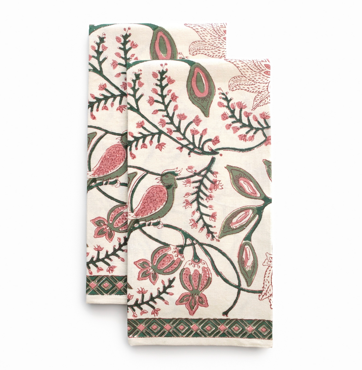 A folded cotton tea towel with a vintage block-print style pattern featuring birds, flowers, and botanical motifs in green, pink, and dark brown on an off-white background.