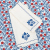 White card with blue floral design on a matching envelope, both on a red and blue floral patterned background.