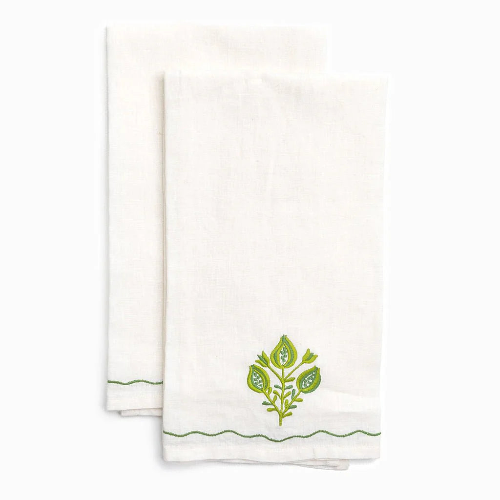 Two white towels with green leaf designs on a white background