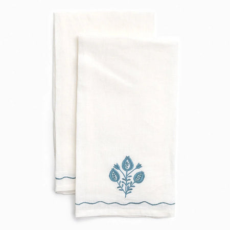 Two white towels with blue floral designs on a white background