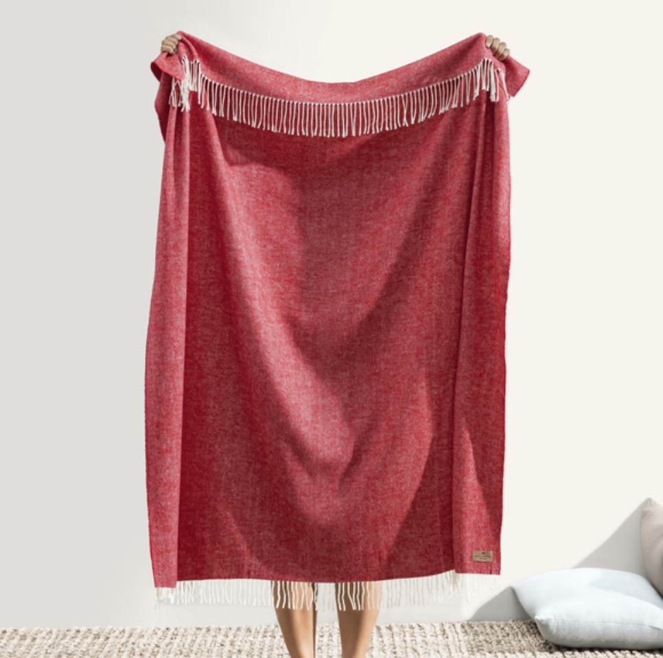 Red throw blanket with fringe on a white background