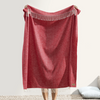 Red throw blanket with fringe on a white background