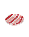 Decorative plate with red and white stripes on a pink background