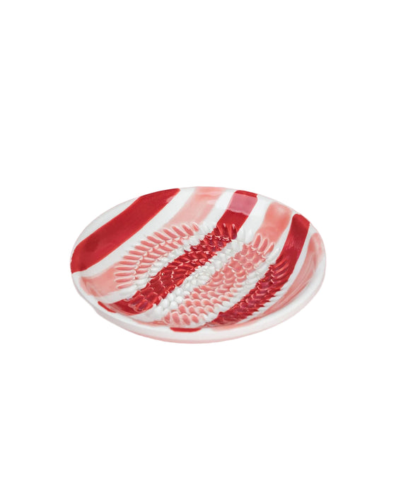 Decorative plate with red and white stripes on a pink background
