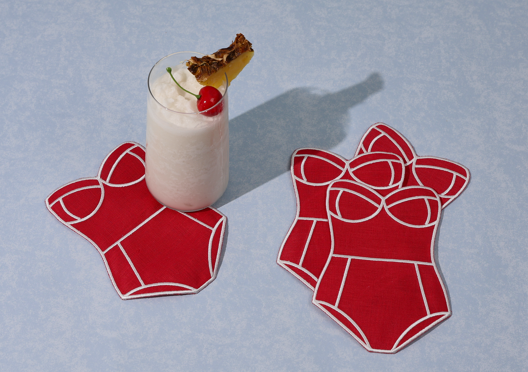 Set of 4 red swim suit cocktail napkins with drink on blue background 