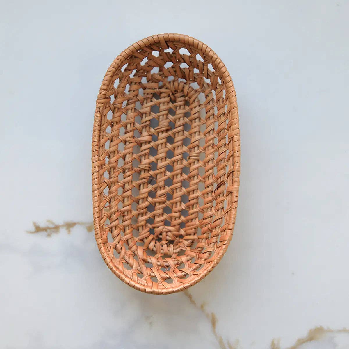 Small, oval rattan storage basket on white background 