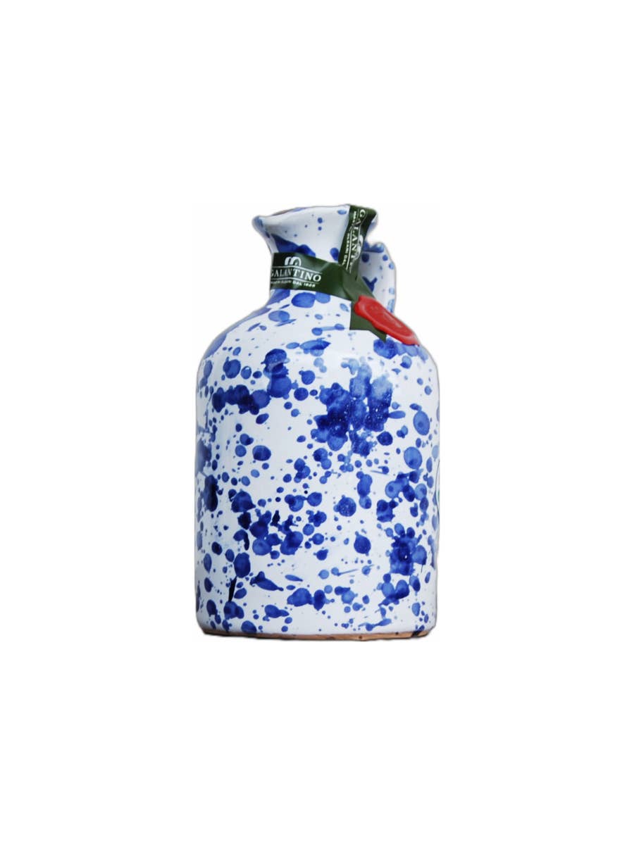 Small cobalt splatter ceramic bottle of olive oil with cork top on white background 